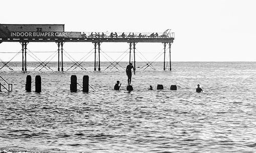 Silhouette people on pier over sea against clear sky