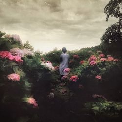 Woman standing on tree against cloudy sky