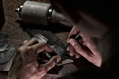 Midsection of man working with leather at table in workshop