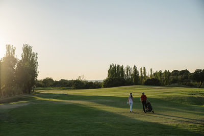 People playing soccer on field against clear sky