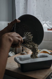 Cropped hands serving food in bowl on table at home