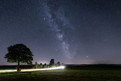 Trees on field against sky at night