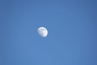 Low angle view of moon against clear blue sky