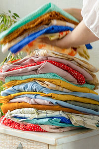 Women's hands take a stack of clothes, in a wardrobe or store.  laundry or clothing recycling