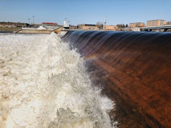 River flowing at dam against sky