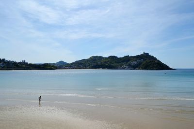 Man running on shore at beach against sky