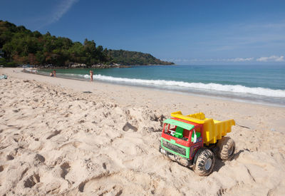 Toy on shore at beach against sky