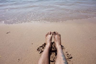 Low section of man relaxing at beach