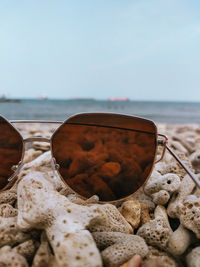 Close-up of sunglasses on beach against clear sky