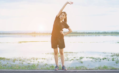 Woman standing at beach against sky