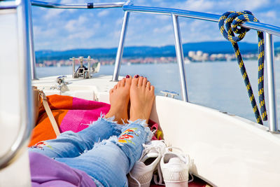 Low section of woman lying on boat sailing in sea