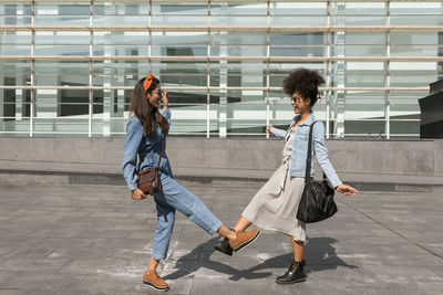 Friends greeting with giving foot bump while standing on rooftop