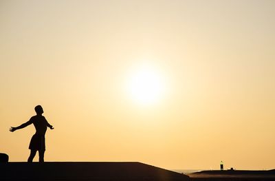 Silhouette man standing against orange sky