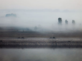 Scenic view of a river against sky in foggy weather