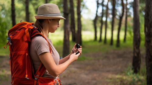 Young woman looking at compass standing in forest