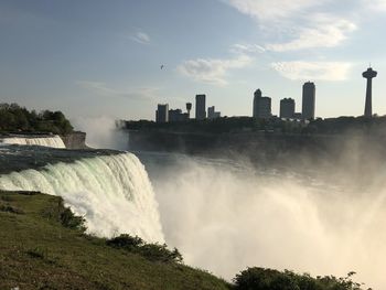 Panoramic view of waterfall in city against sky