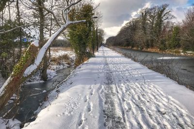 Road by river against sky during winter