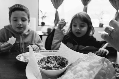 Cute siblings eating food at restaurant