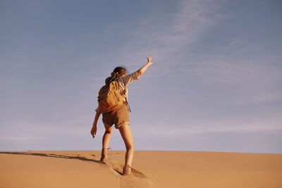 Full length of woman standing on sand at beach against sky