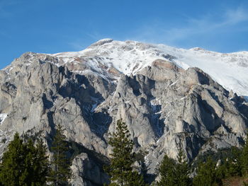 Low angle view of snowcapped mountains against blue sky