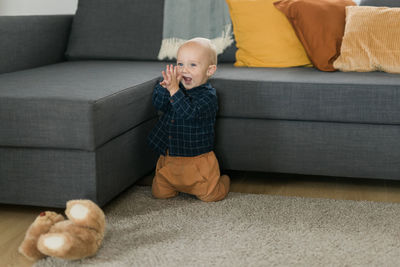 Low section of boy sitting on sofa at home