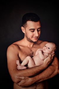 Portrait of father with baby against black background