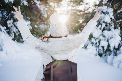 Back view of young woman at sunset in snowy mountain. nature and fun concept. winter season