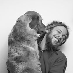 Portrait of man with dog against white background