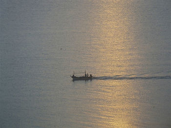 Boat sailing in sea against sky at sunset