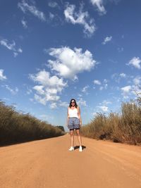 Woman standing on dirt road against sky