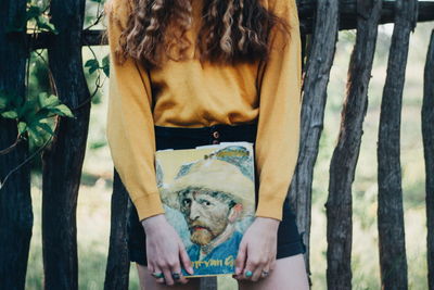 Full length of woman holding plants against trees