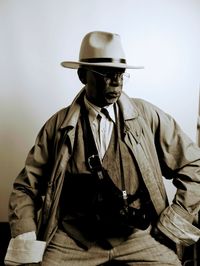 Portrait of man wearing hat standing against gray background