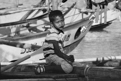 Full length of boy sitting on wood