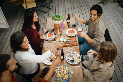 High angle view of friends enjoying drinks while having food during garden party