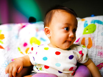 Close-up of cute baby girl drooling while sitting on chair at home