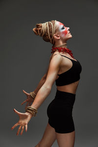 Portrait of woman with arms raised standing against black background