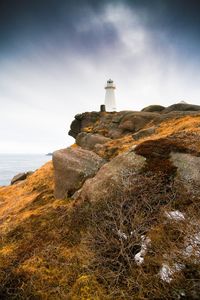 Lighthouse by sea against sky