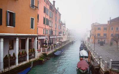 Canal amidst buildings in city against sky