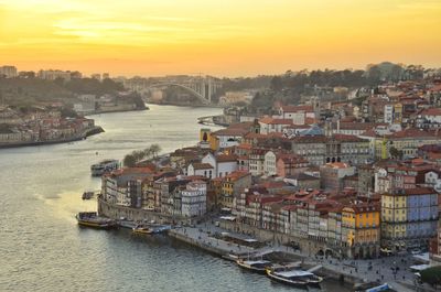 High angle view of river by buildings against sky during sunset