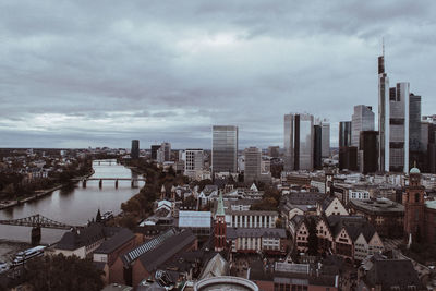 High angle view of city buildings against cloudy sky