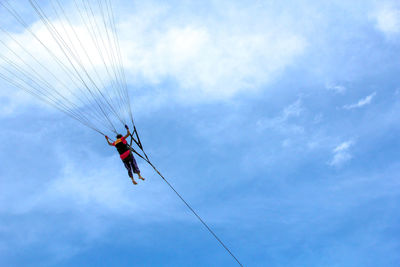 Low angle view of people on rope against sky