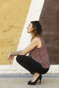 Side view of a young woman against wall