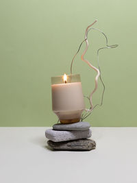 Close-up of illuminated candles on table against wall