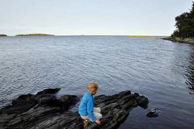 Rear view of boy looking at sea against sky