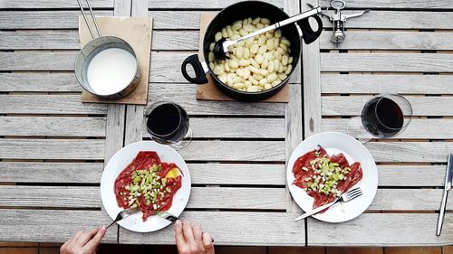 Cropped image of hands having meat with pasta on table