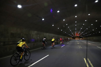 People riding bicycle on road in illuminated tunnel