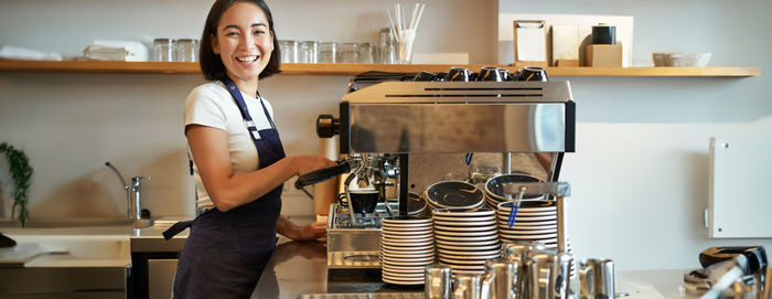 Portrait of young woman standing in kitchen