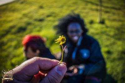 Midsection of people holding flowering plant