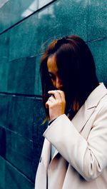 Portrait of young woman looking away against wall