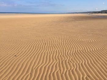 Sand dunes at beach against sky